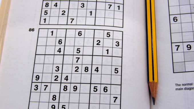 Sudoku puzzle book with pencil laying between the pages