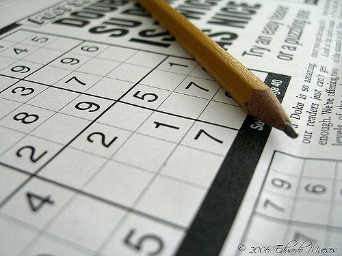 Pencil resting on newspaper with sudoku puzzle